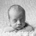 Picture of a baby with hands under the chin featured in a review of baby photography