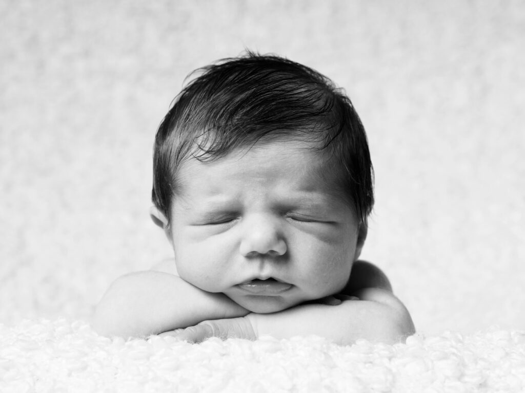 Beautiful black and white photo of a baby with hands under the chin