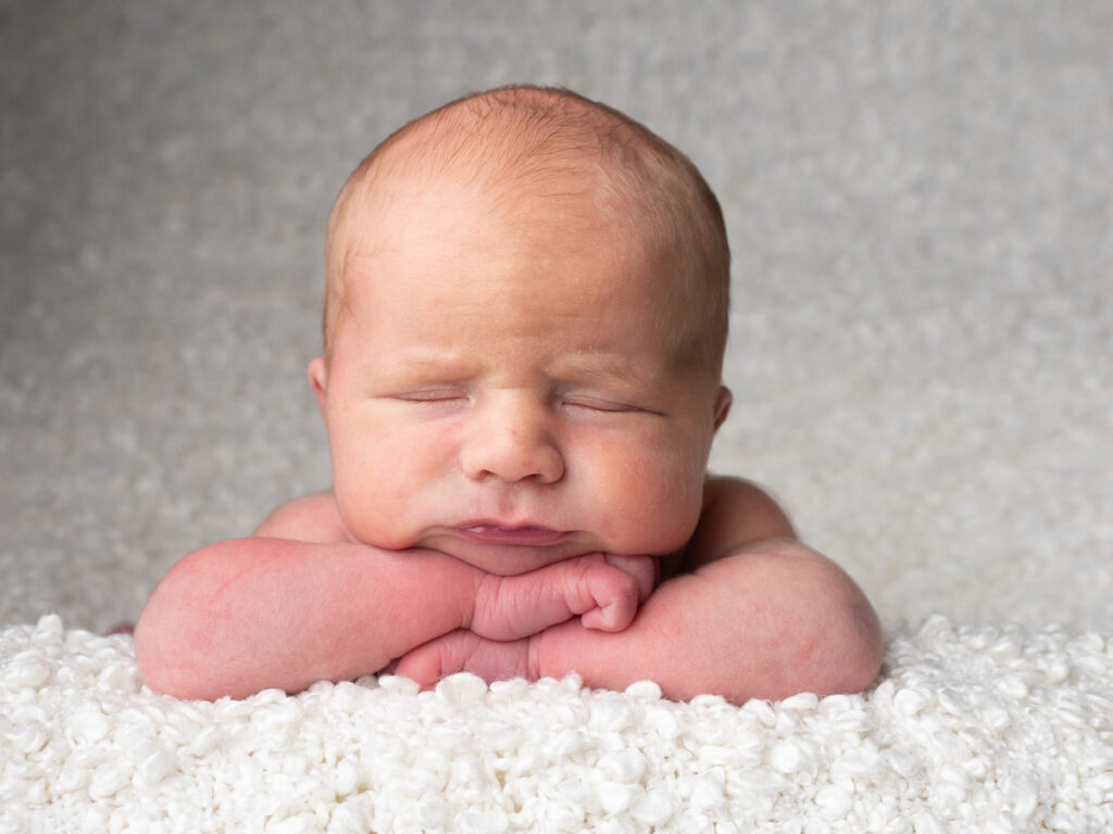 baby with hands on the chin posing for a photograph