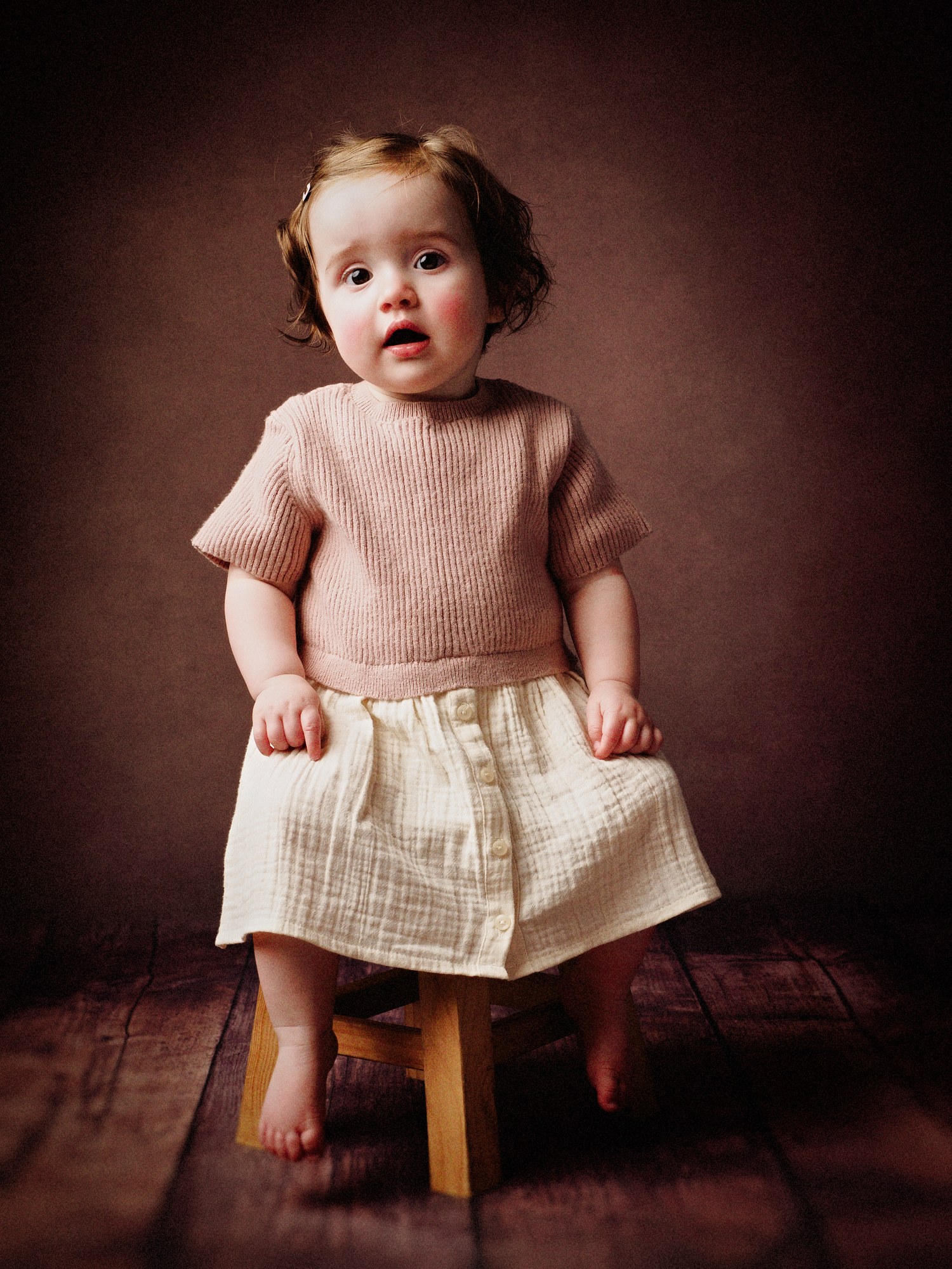 Baby sitting on a little wooden stool