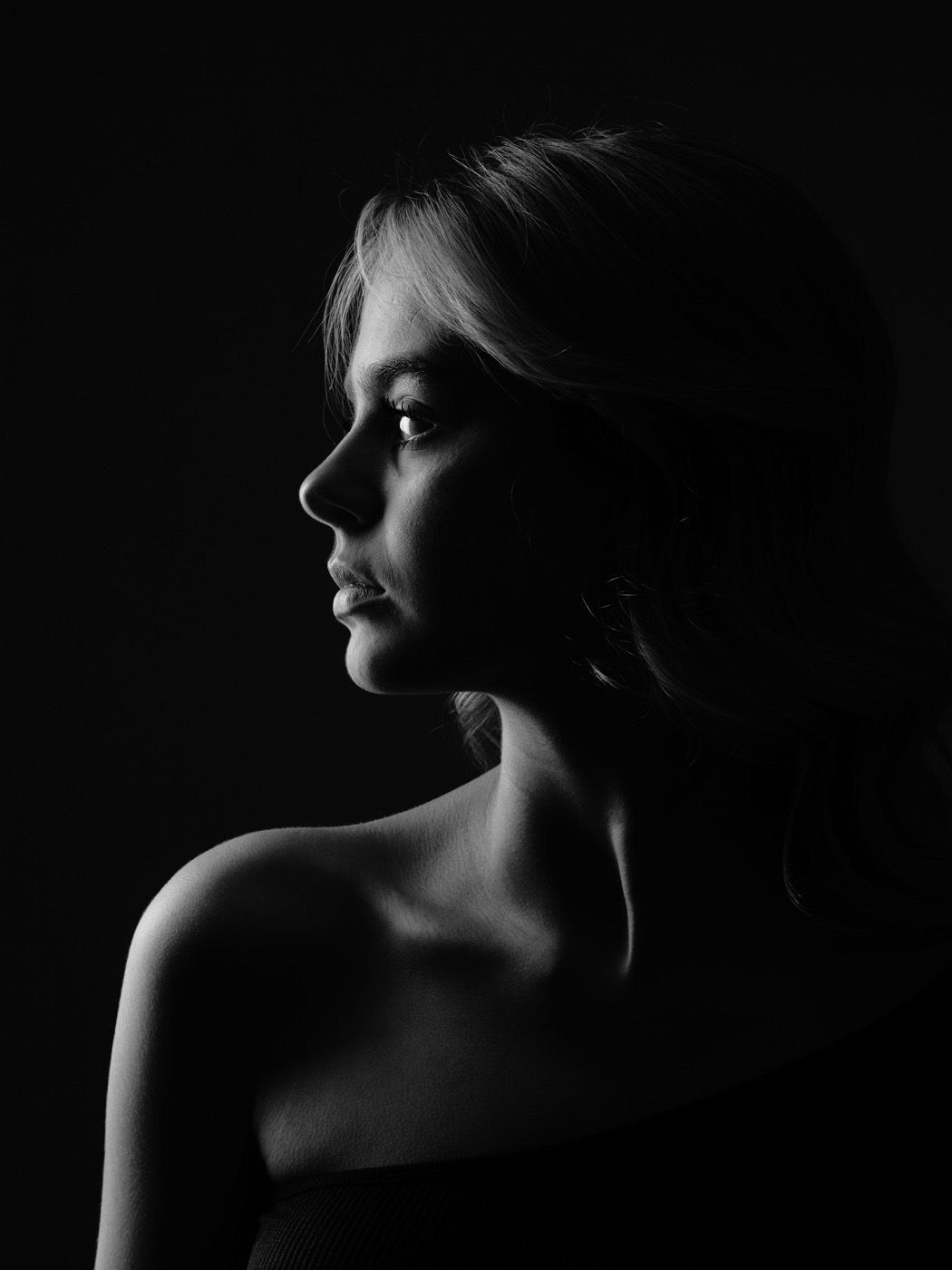 Low key profile portrait of a teenage girl on black, black and white