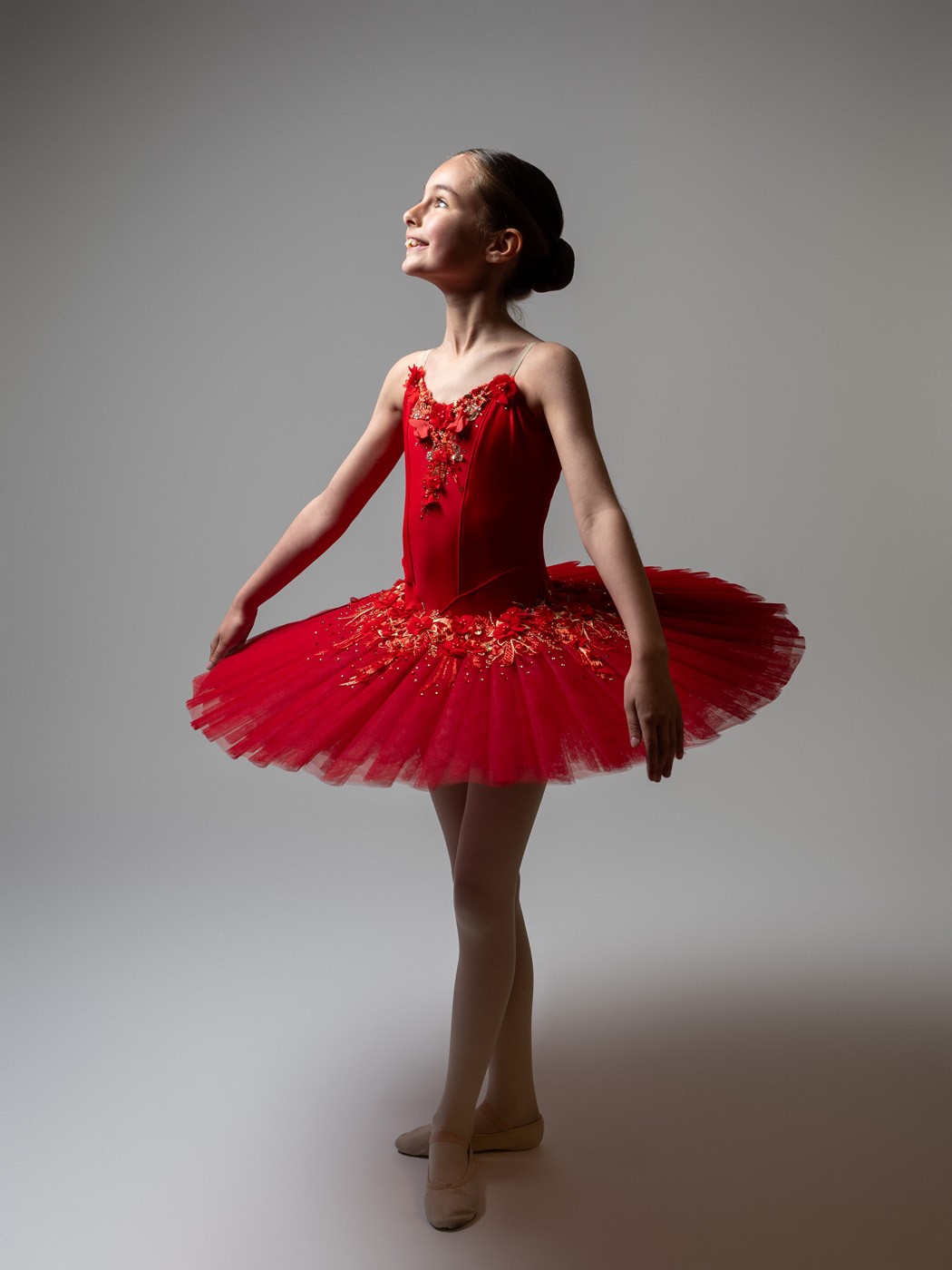 Smiling ballerina in a red tutu looking upwards