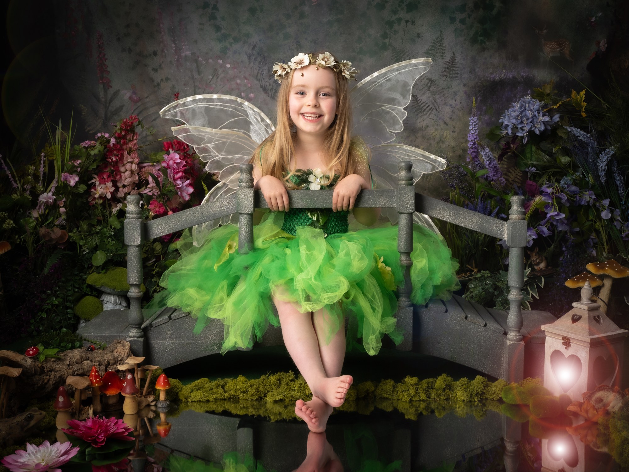Smiling girl dressed as a fairy on a little bridge in an enchanted garden