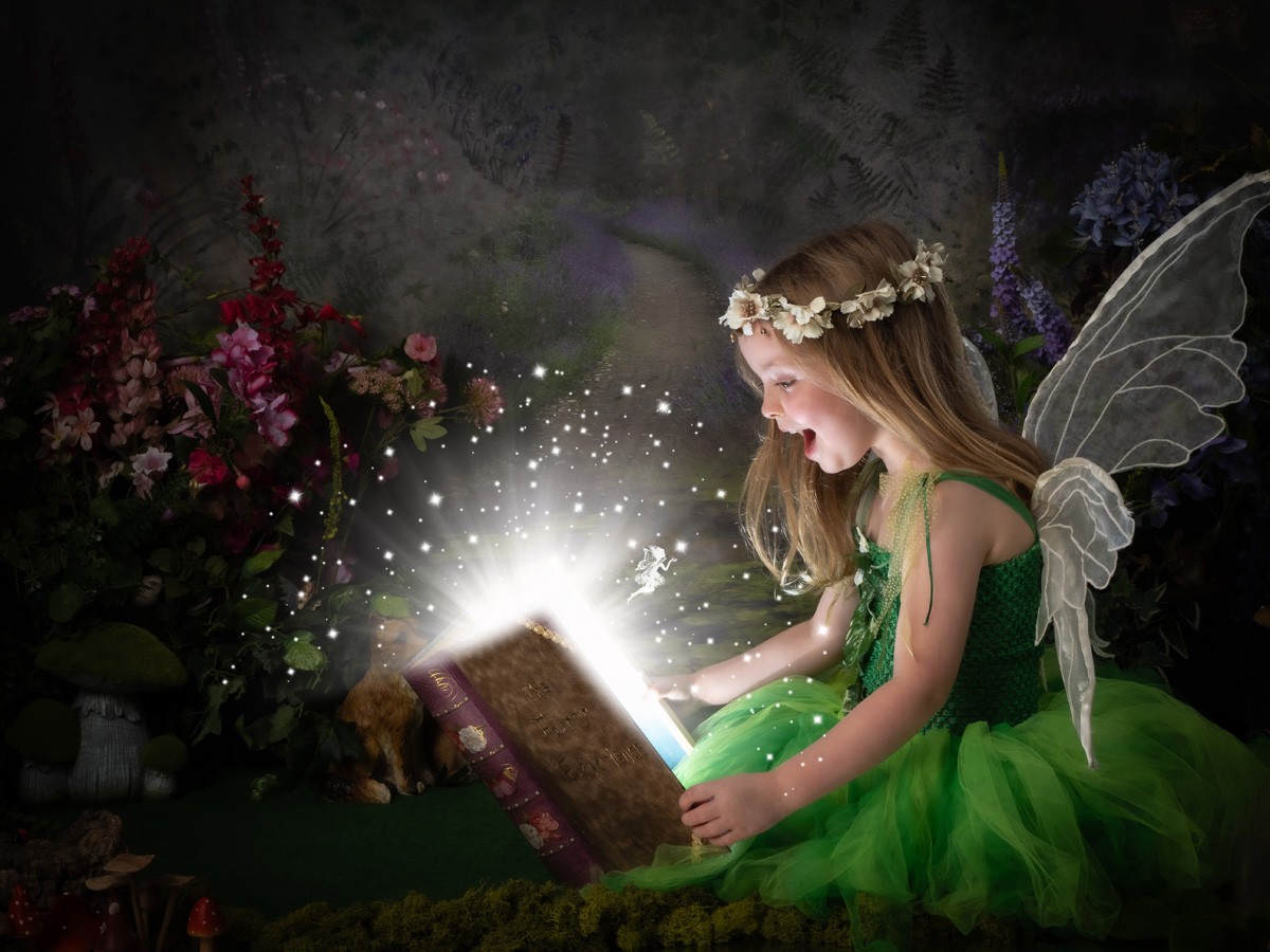 Amazed fairy in green opening a sparkling magic book