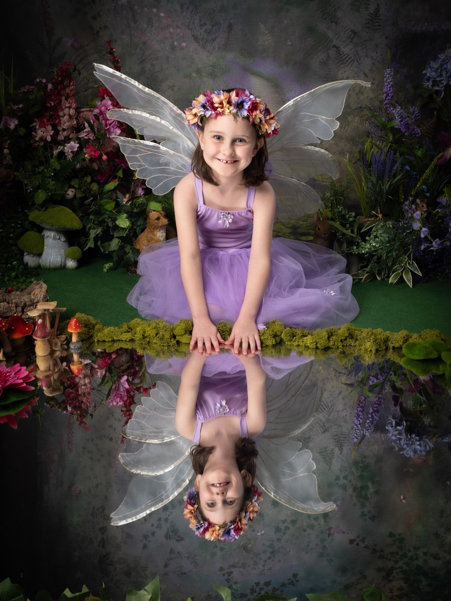 Smiling fairy in lilac leaning over a reflecting pool