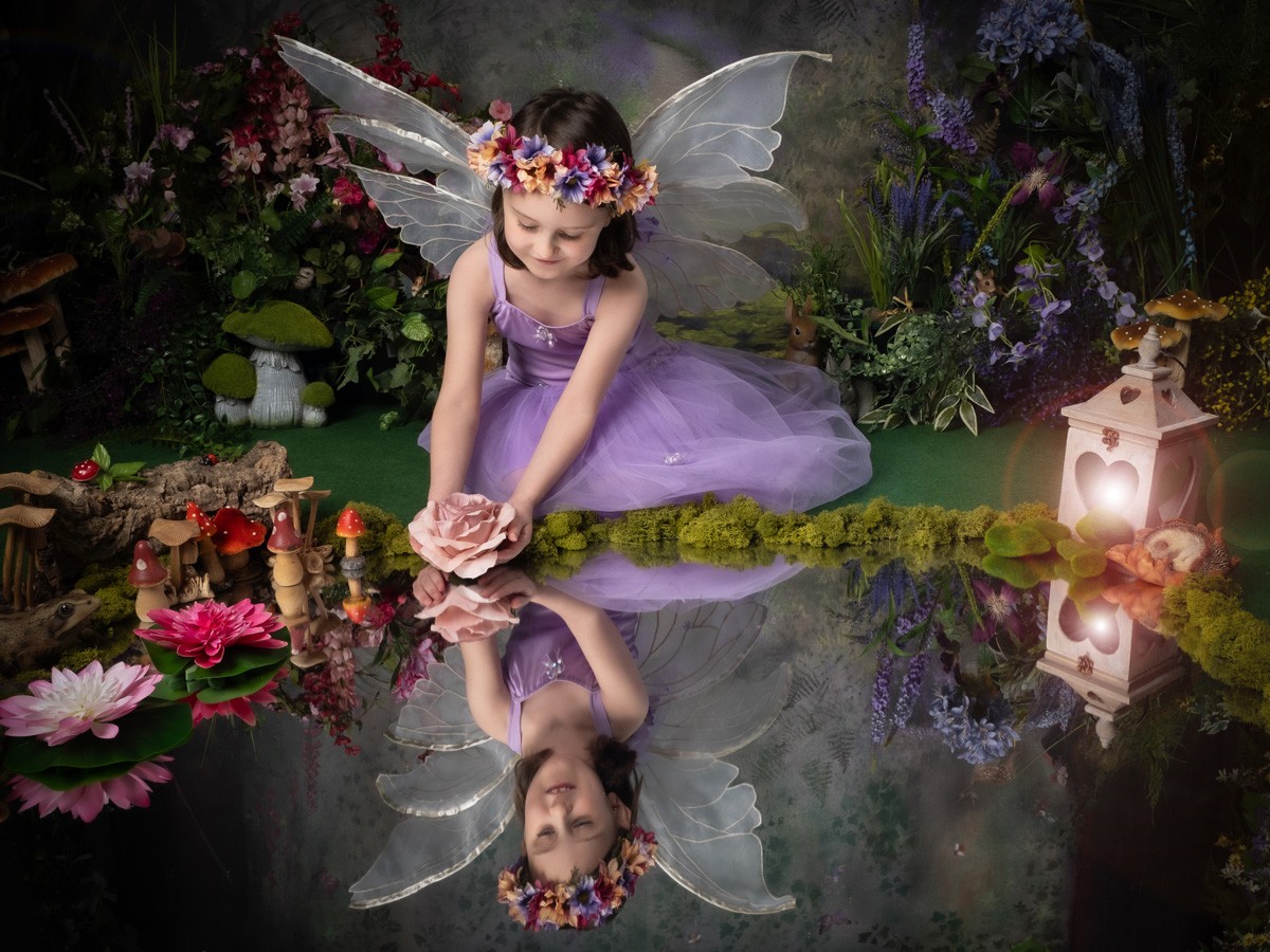 Fairy in lilac holding a rose over a reflecting pool