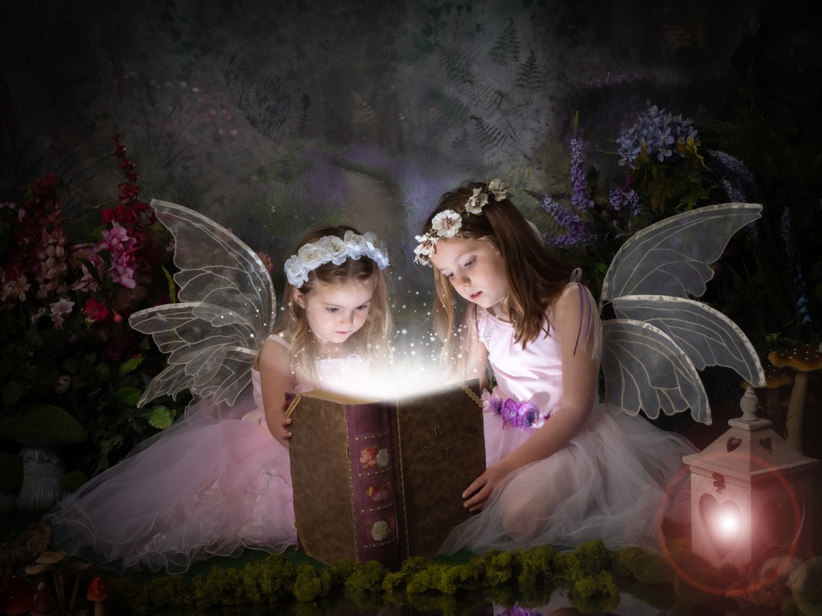 Two fairy sisters opening a glowing magic book
