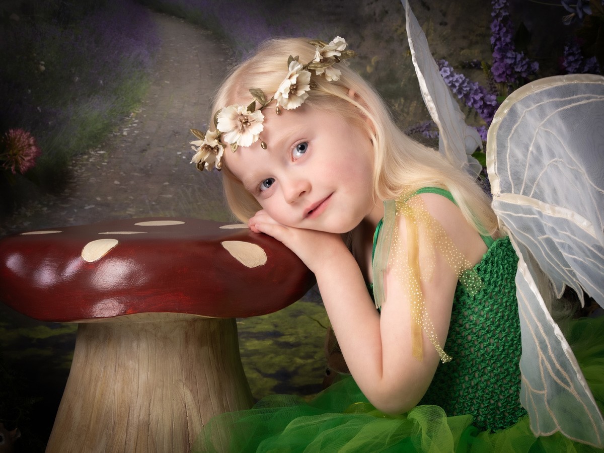 Blonde fairy resting her head on a red toadstool