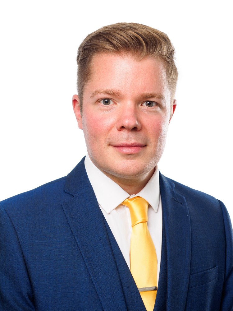 Business headshot of a man in a blue suit and yellow tie on white