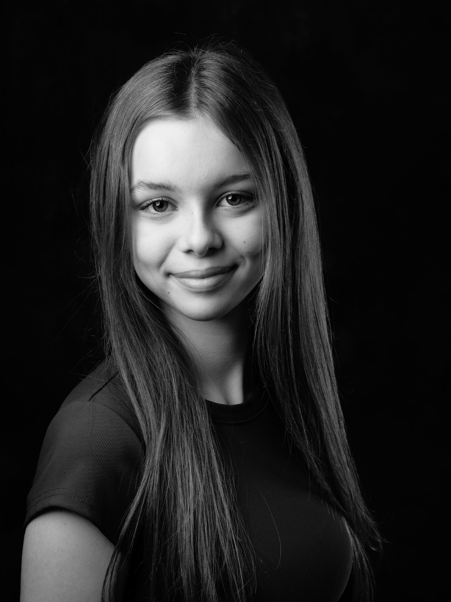 Black and white headshot of a smiling teenage actor on black