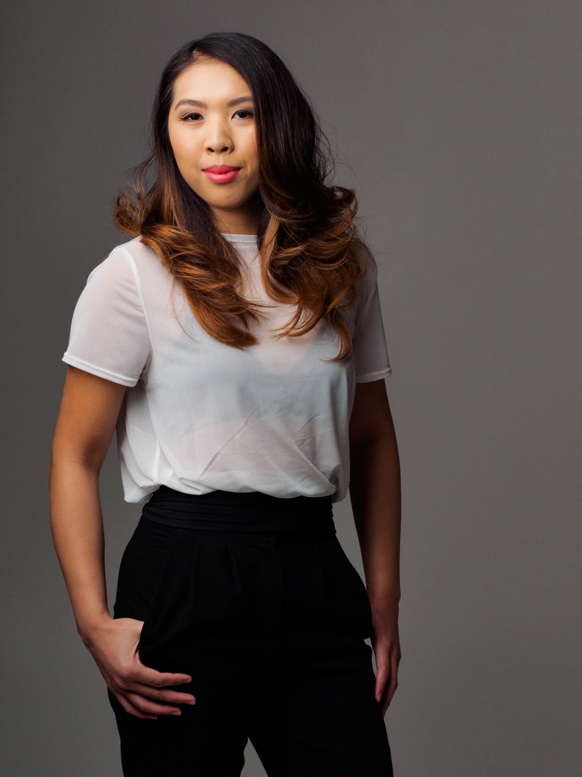 Three-quarter business portrait of a woman in a white top and black trousers on grey
