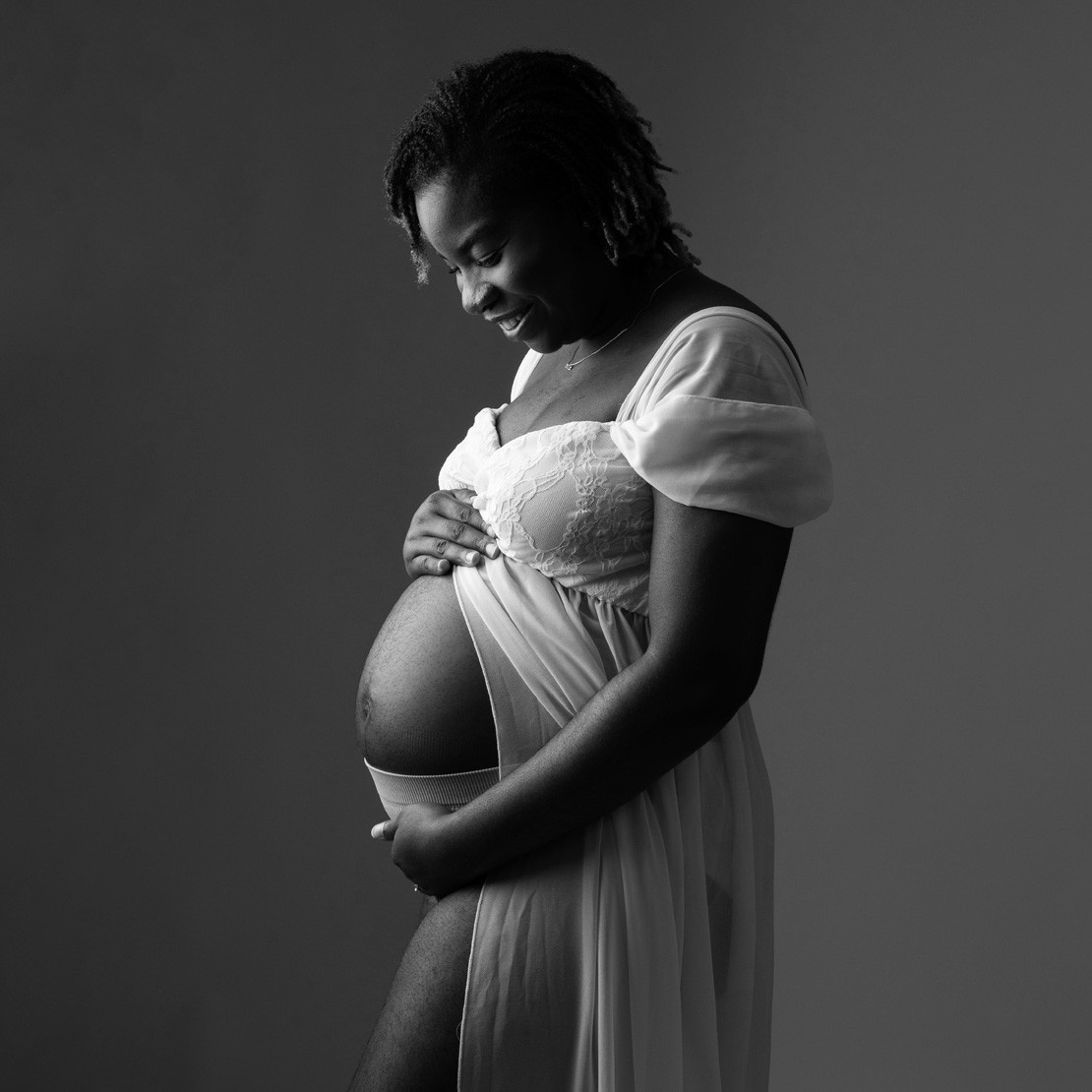 Smiling mum-to-be in a white gown, black and white