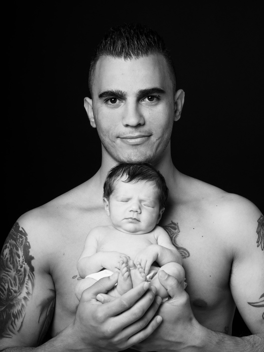 Newborn cradled in dad’s hands, black and white