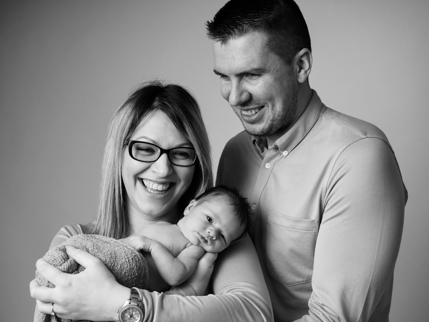 Parents laughing with their newborn, black and white