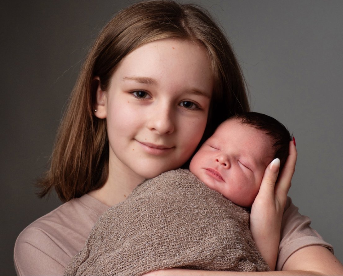 Big sister cuddling her newborn sibling